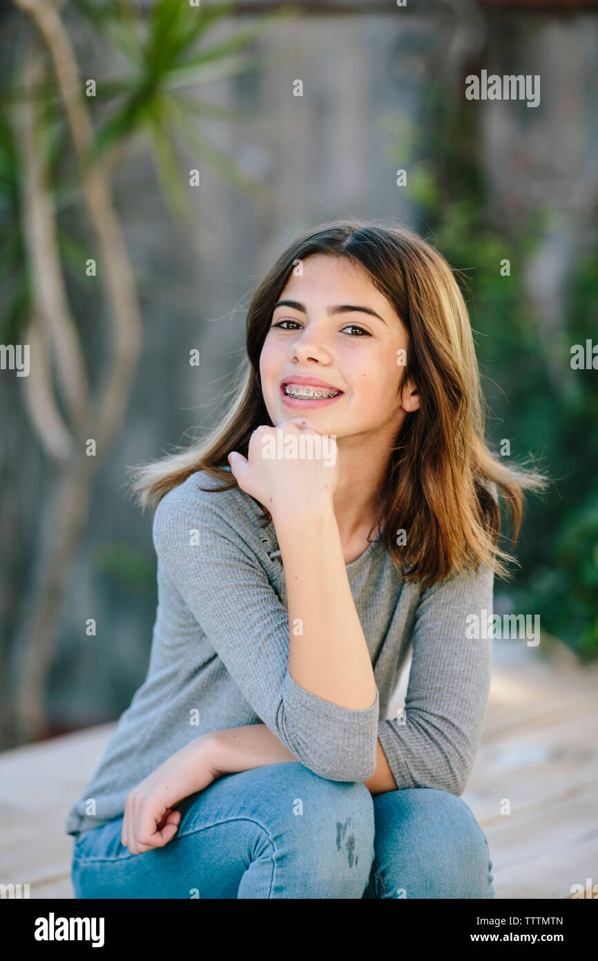 Retrato de niña sonriente sentado en la mesa en el patio Foto de stock