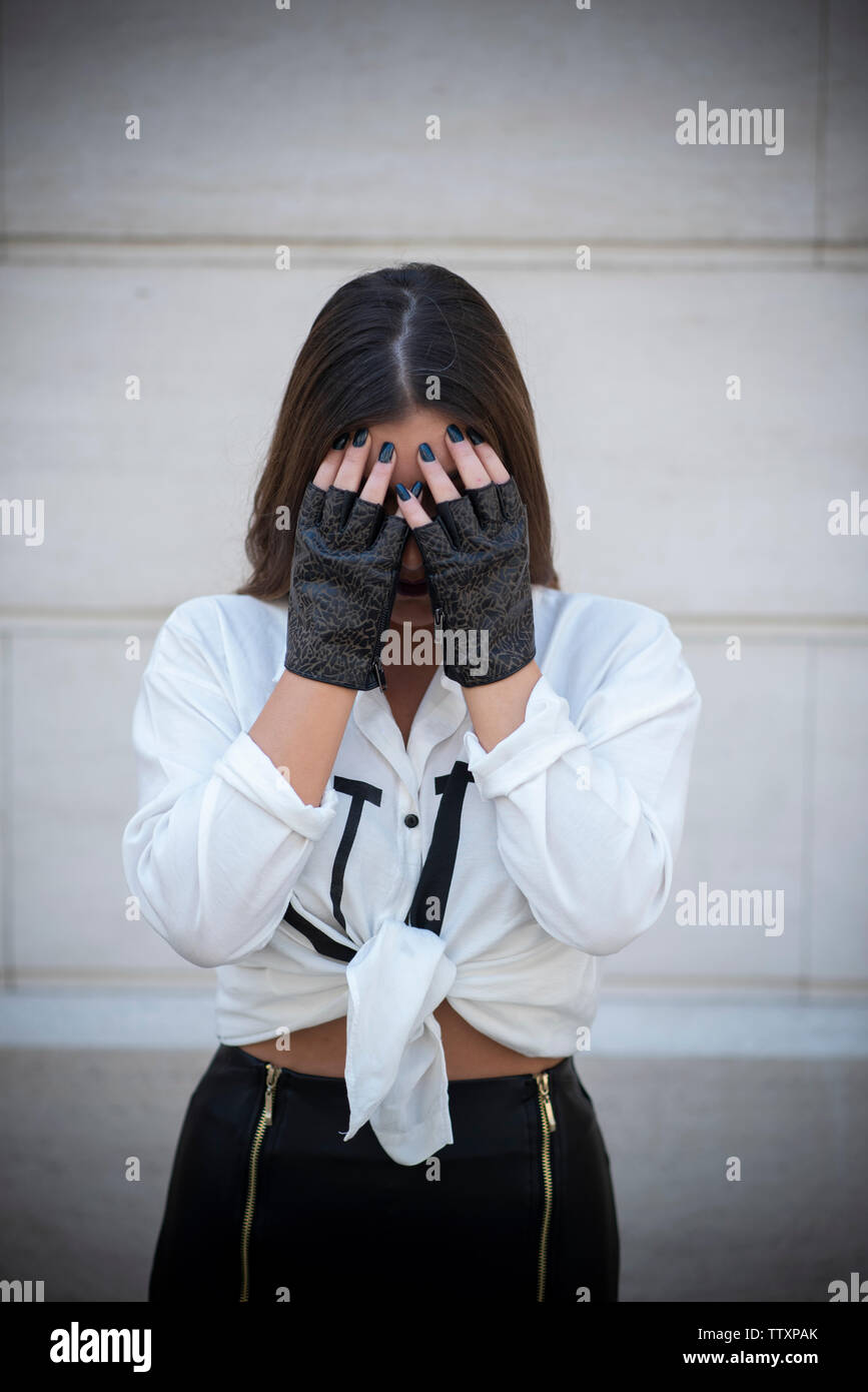 Joven mujer vistiendo sin dedos guantes de cuero ocultando la cara con las  manos Fotografía de stock - Alamy