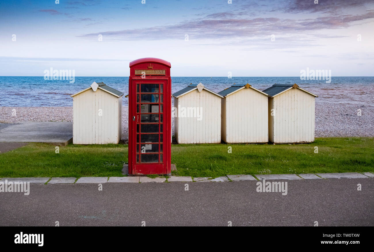 Cuadro teléfono rojo y cabañas de playa por el mar de Budleigh Salterton, Devon, Reino Unido Foto de stock