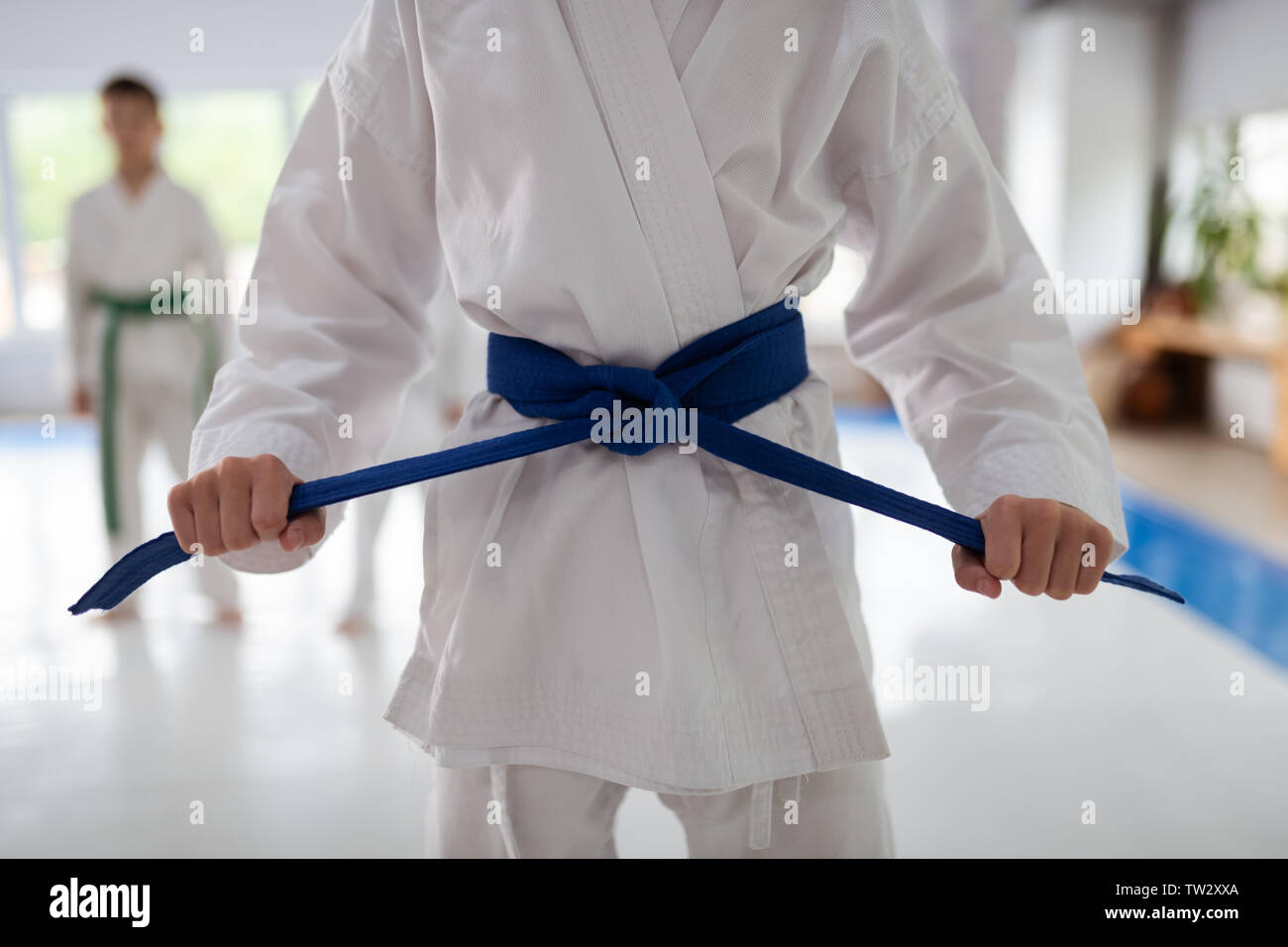 Cinturón azul. Cerca de vestida de kimono blanco atado a su cinturón azul  antes de practicar Aikido Fotografía de stock - Alamy