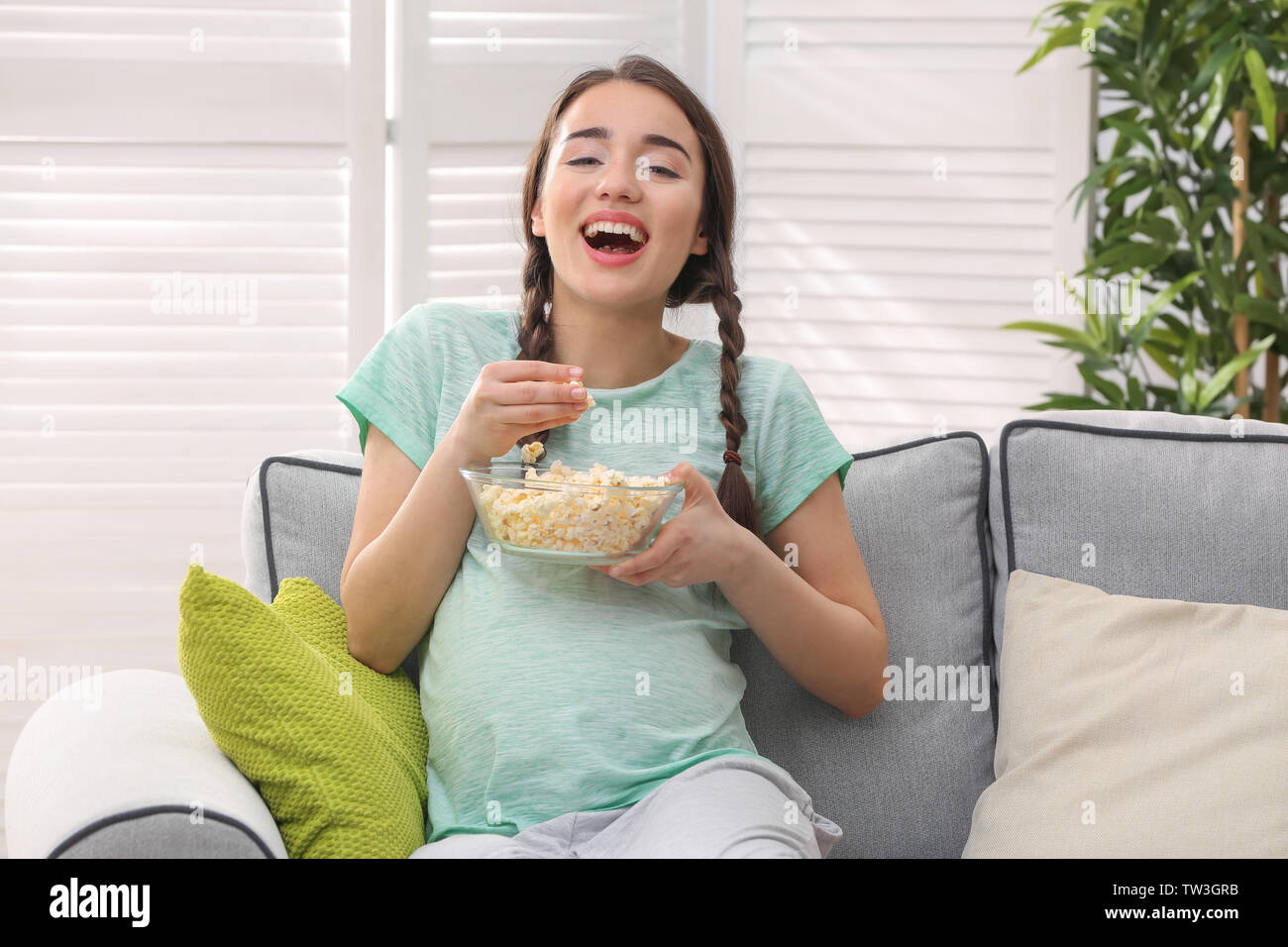hermosa mujer embarazada está comiendo palomitas mientras mira la película  sola, ella se sienta en el sofá, disfrutar de tiempo Fotografía de stock -  Alamy