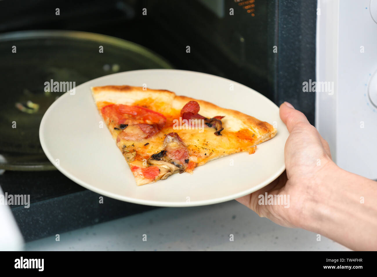 Mujer poniendo la placa con una porción de pizza en horno de microondas.  Cocinar para un concepto Fotografía de stock - Alamy