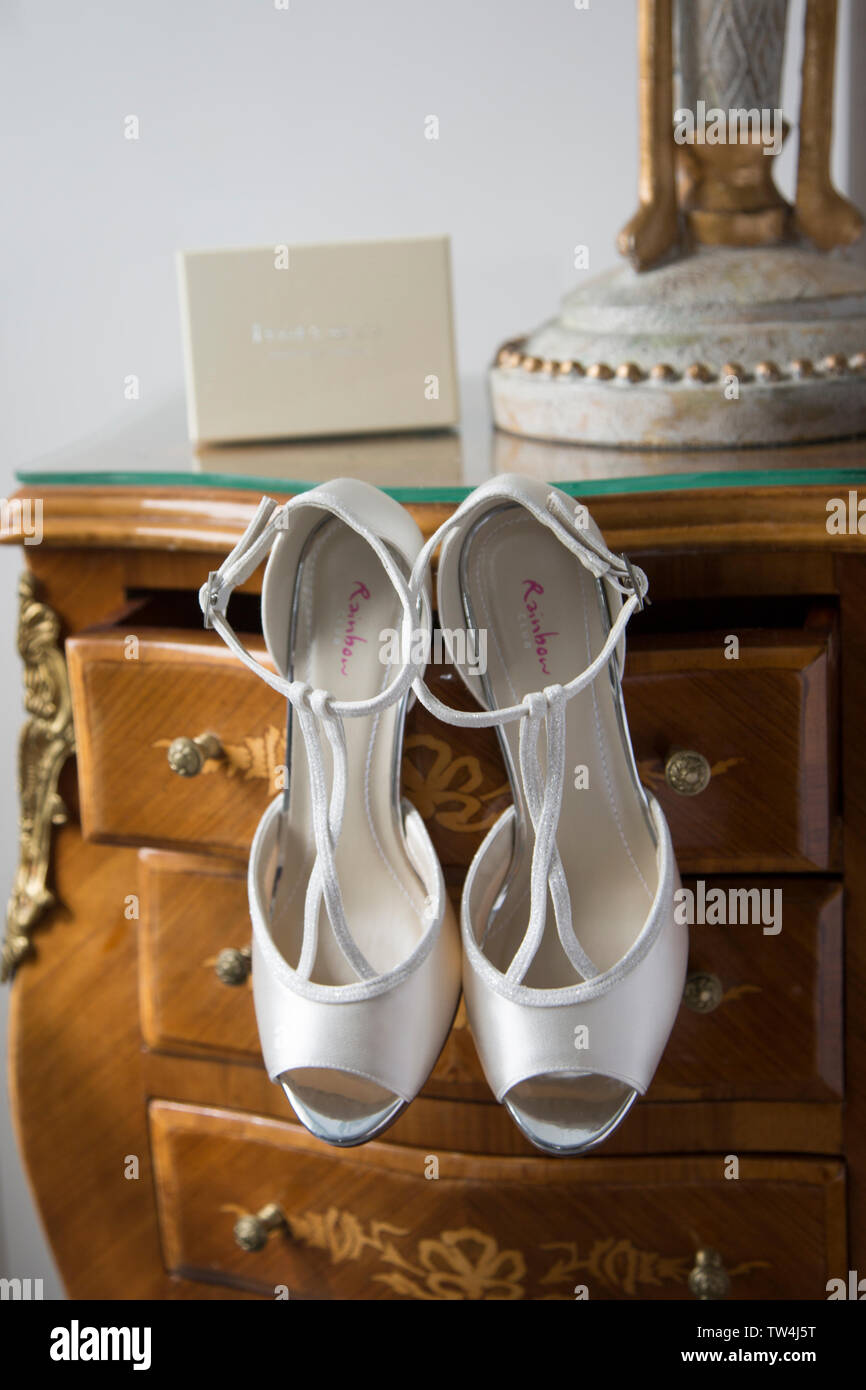 Blanco satinado y brillante novias zapatos de boda, colgando de un empate  en la suite nupcial, esperando a ser usados en el día de la boda Fotografía  de stock - Alamy