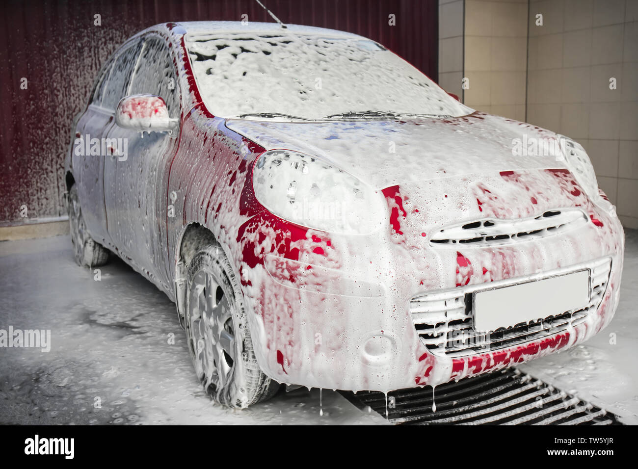 Lavar el coche rojo con espuma Foto de stock 1879119892