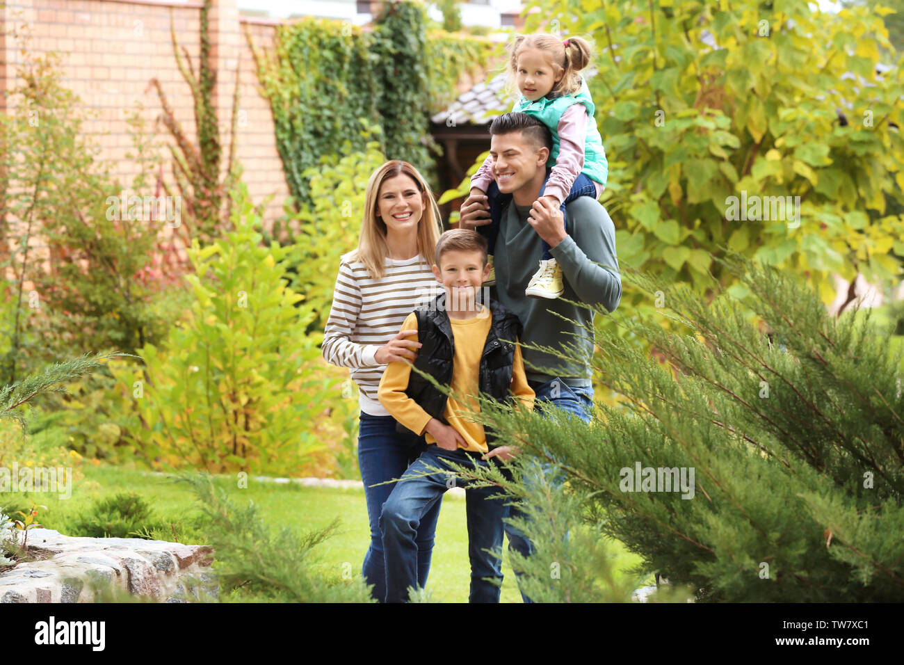 Familia Feliz en el jardín cerca de su casa Foto de stock