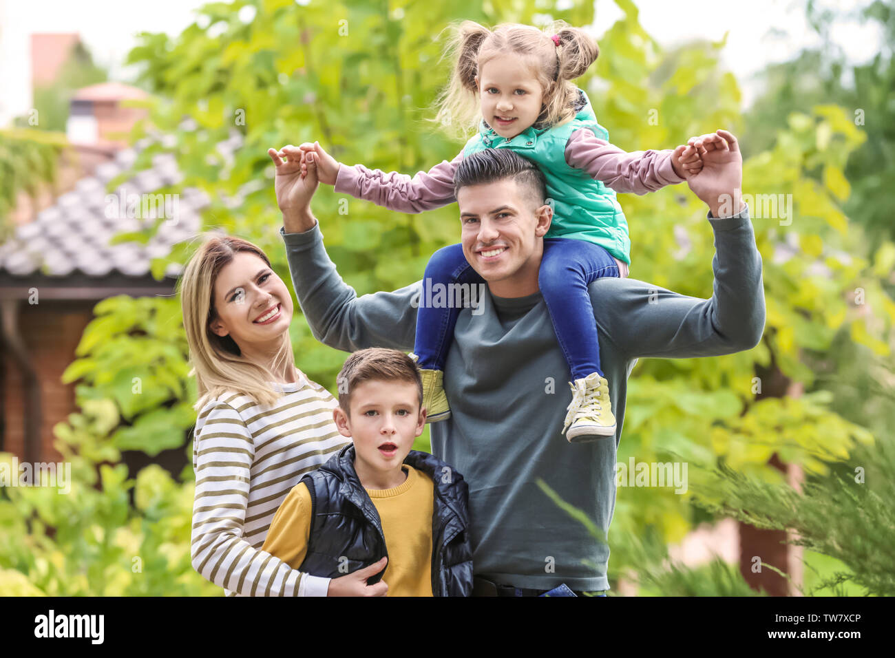 Familia Feliz en el jardín cerca de su casa Foto de stock