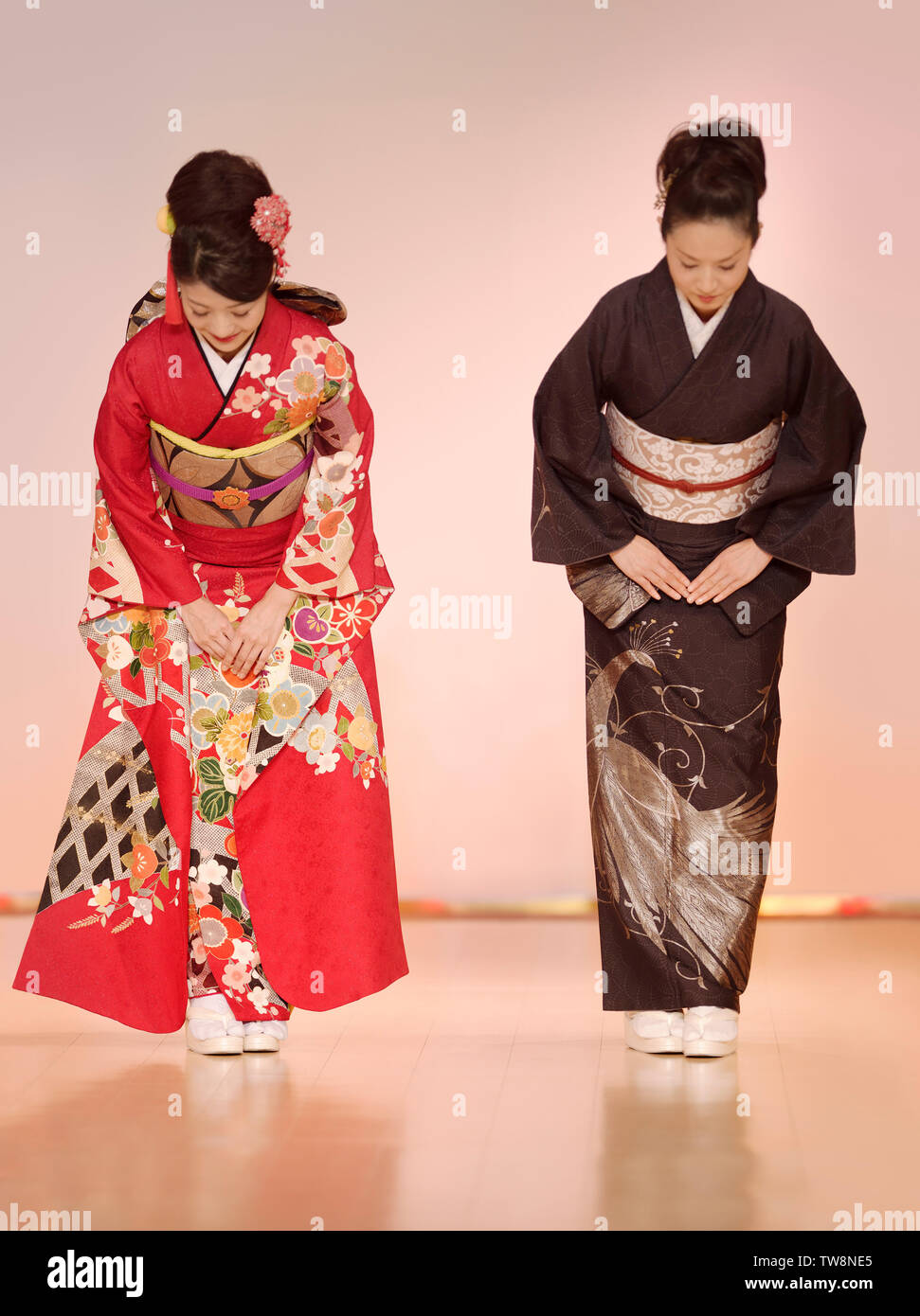 Licencia disponible en MaximImages.com - Mujeres japonesas en elegante kimono rojo y negro que se inclinan en un desfile de moda en Kyoto, Japón. Foto de stock