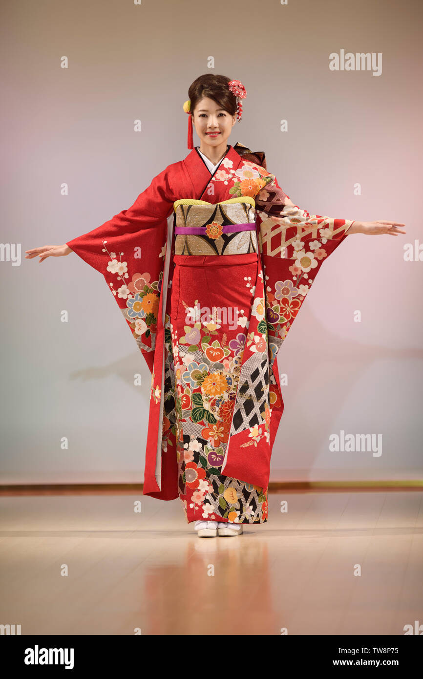 Mujer japonesa en un hermoso color rojo kimono con mangas largas y un golden obi. Kimono Fashion show en Kyoto, Japón. Foto de stock