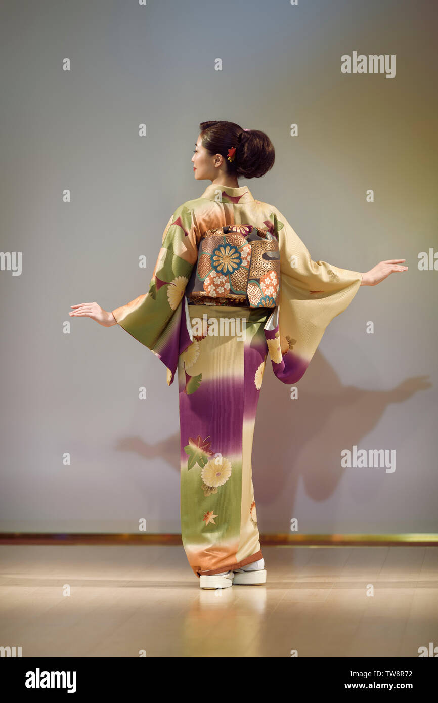 Atrás de una mujer japonesa vistiendo un hermoso y verde amarillo con kimono obi en un desfile de moda en Kyoto, Japón. Foto de stock