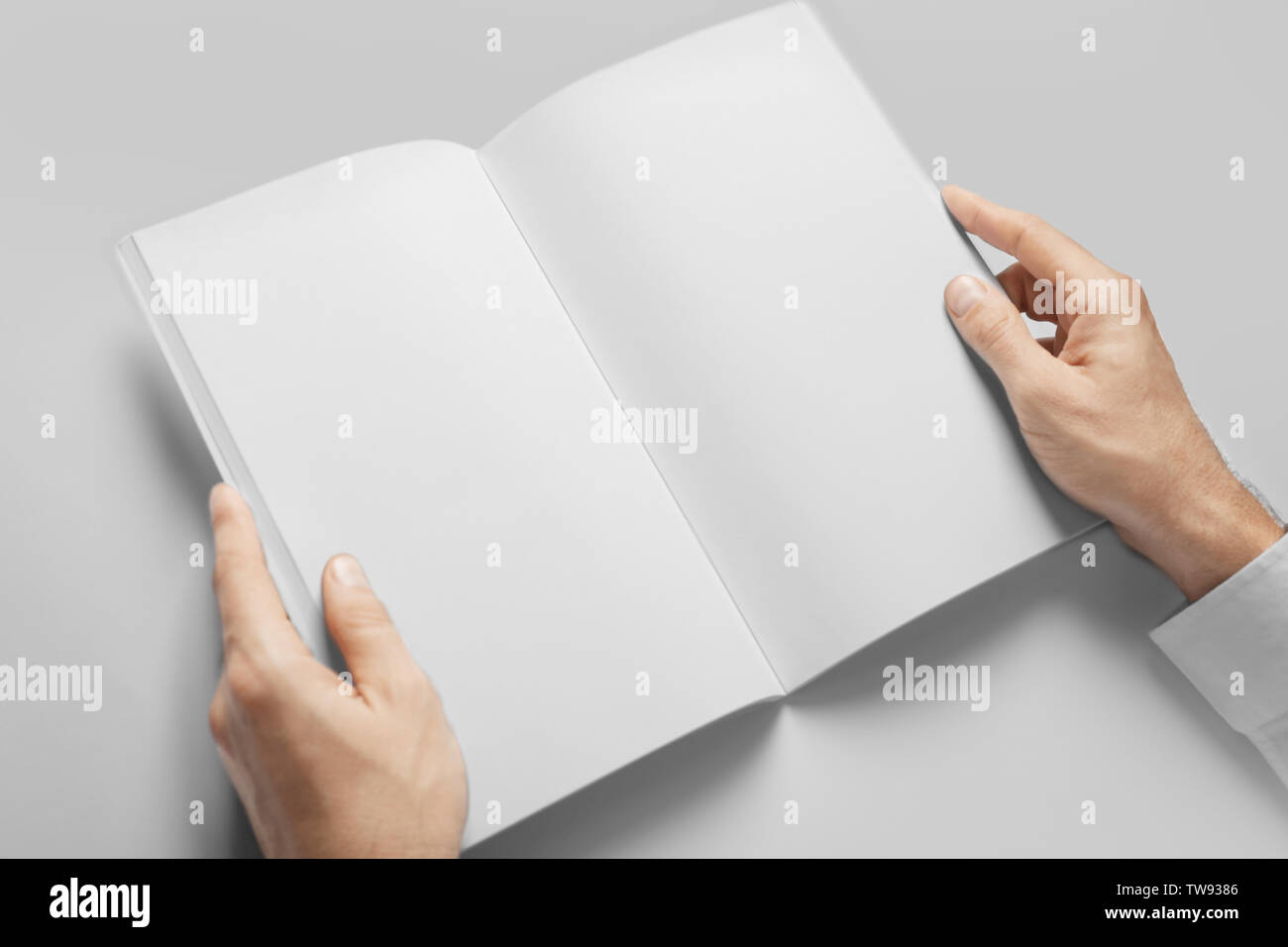 Hombre sujetando libro con páginas en blanco sobre fondo blanco. Maqueta de diseño Foto de stock