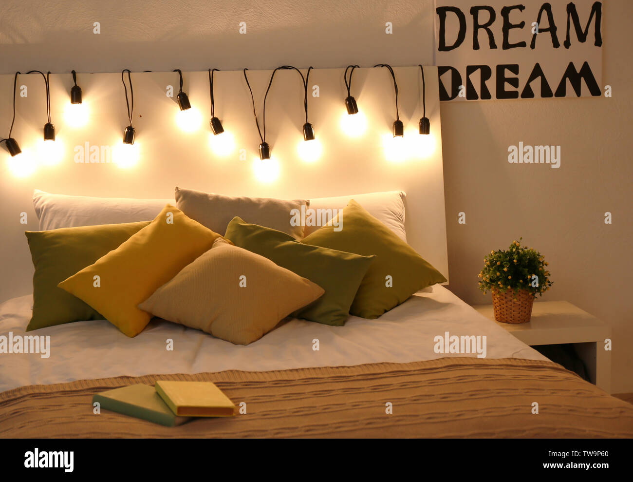 Cómoda cama doble decorado con luces de hadas en la noche Foto de stock