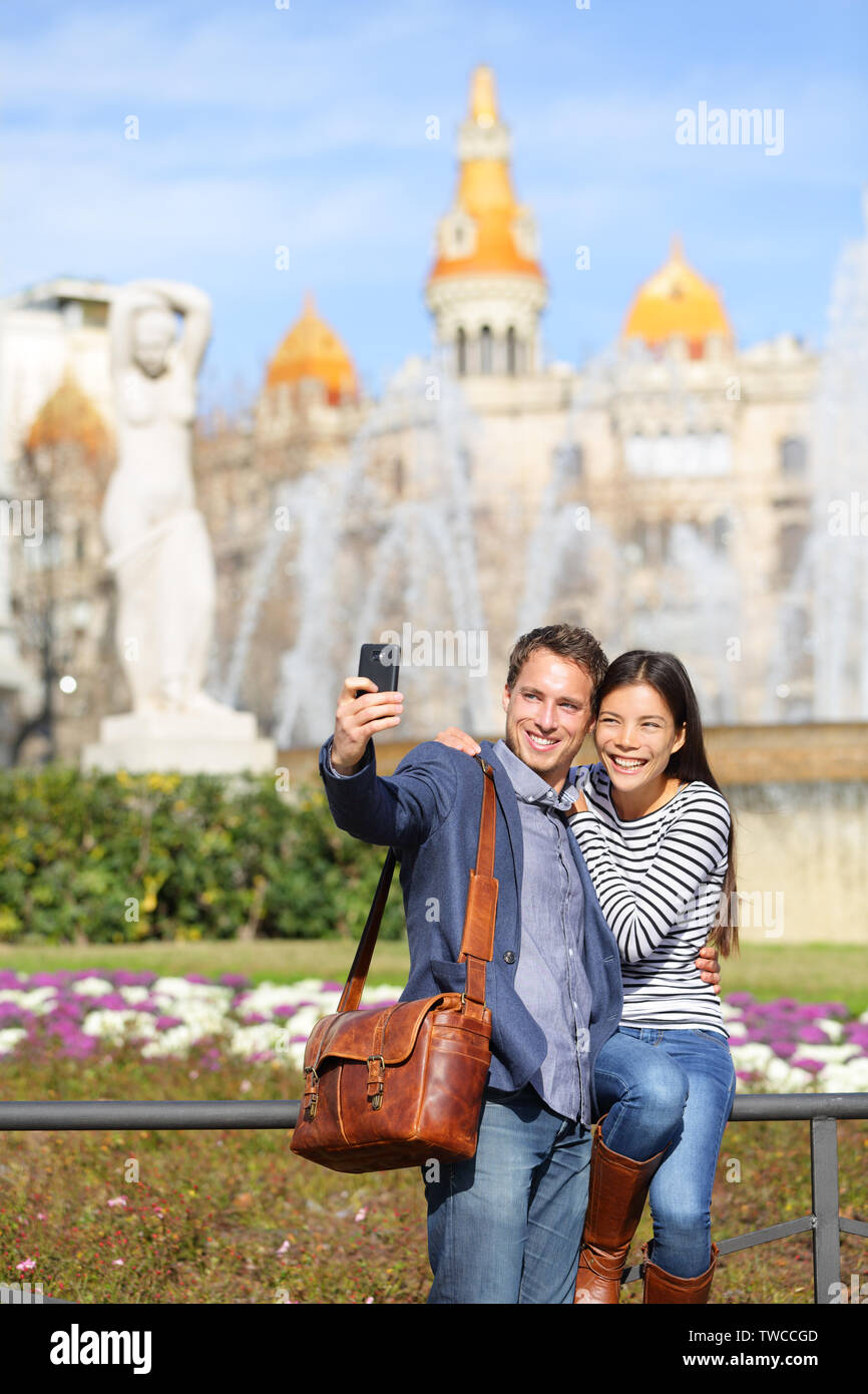 Los viajes turísticos par teniendo selfie en Barcelona con la cámara del  teléfono inteligente. Moda cool urbano Cauasian pareja, hombre, mujer  asiática viajando juntos, Plaça de Catalunya, la Plaza de Cataluña,  Barcelona,