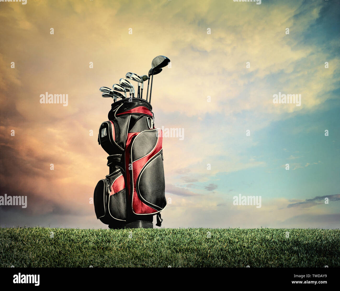 Rojo y negro, bolsa de golf con los clubes en la hierba contra las nubes dramático Foto de stock