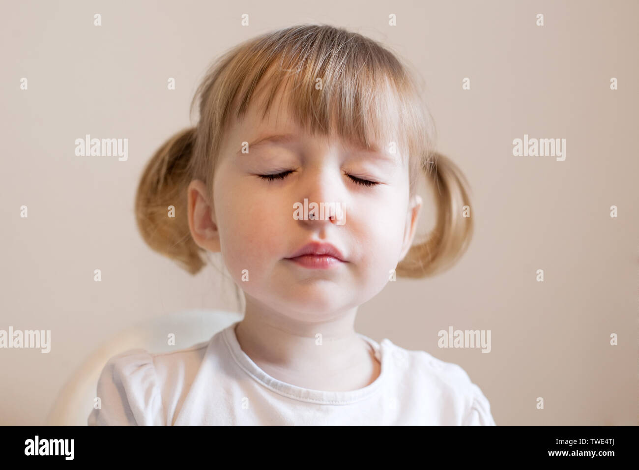 Funny niña con dos cute pigtails, quiff y ojos cerrados Foto de stock