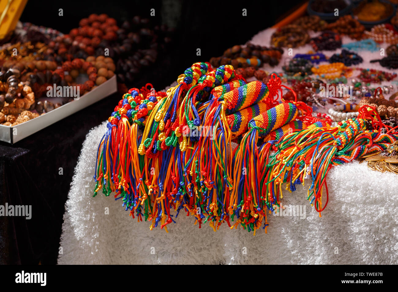 Coloridos colgantes en la pantalla para la venta de un mercado. Accesorios, joyas, budismo, artesanía, arte, hechos a mano, hilo, hilo, lana, tejidos de colores. Foto de stock