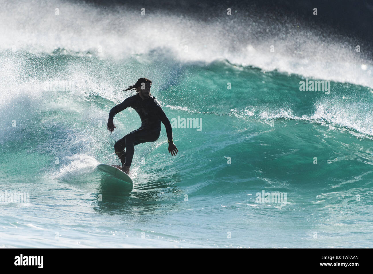 Surf espectacular acción como un surfista cabalga una ola de un mar color jade en Fistral en Newquay en Cornualles. Foto de stock
