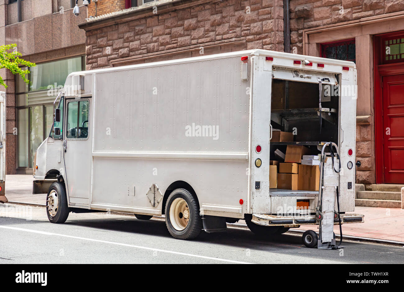 Entregas Puerta a puerta. Los paquetes en un camión de color blanco con la puerta abierta, estacionado en una calle en el centro de la ciudad, Nueva York Foto de stock