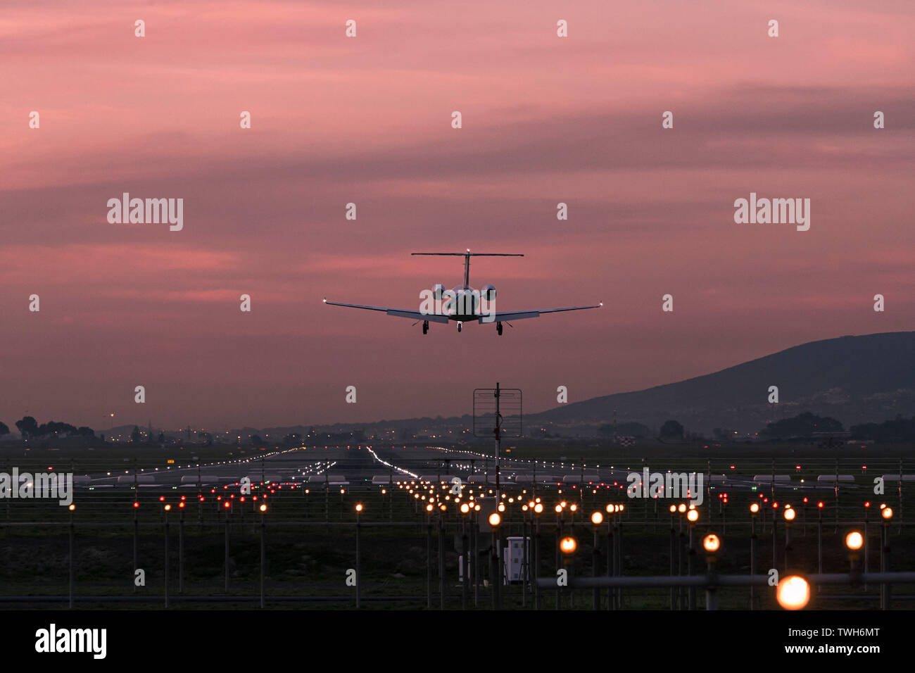 Los pequeños aviones que aterrizan en el Aeropuerto Internacional de Ciudad del Cabo al anochecer con la pista de aterrizaje claramente iluminado. Foto de stock
