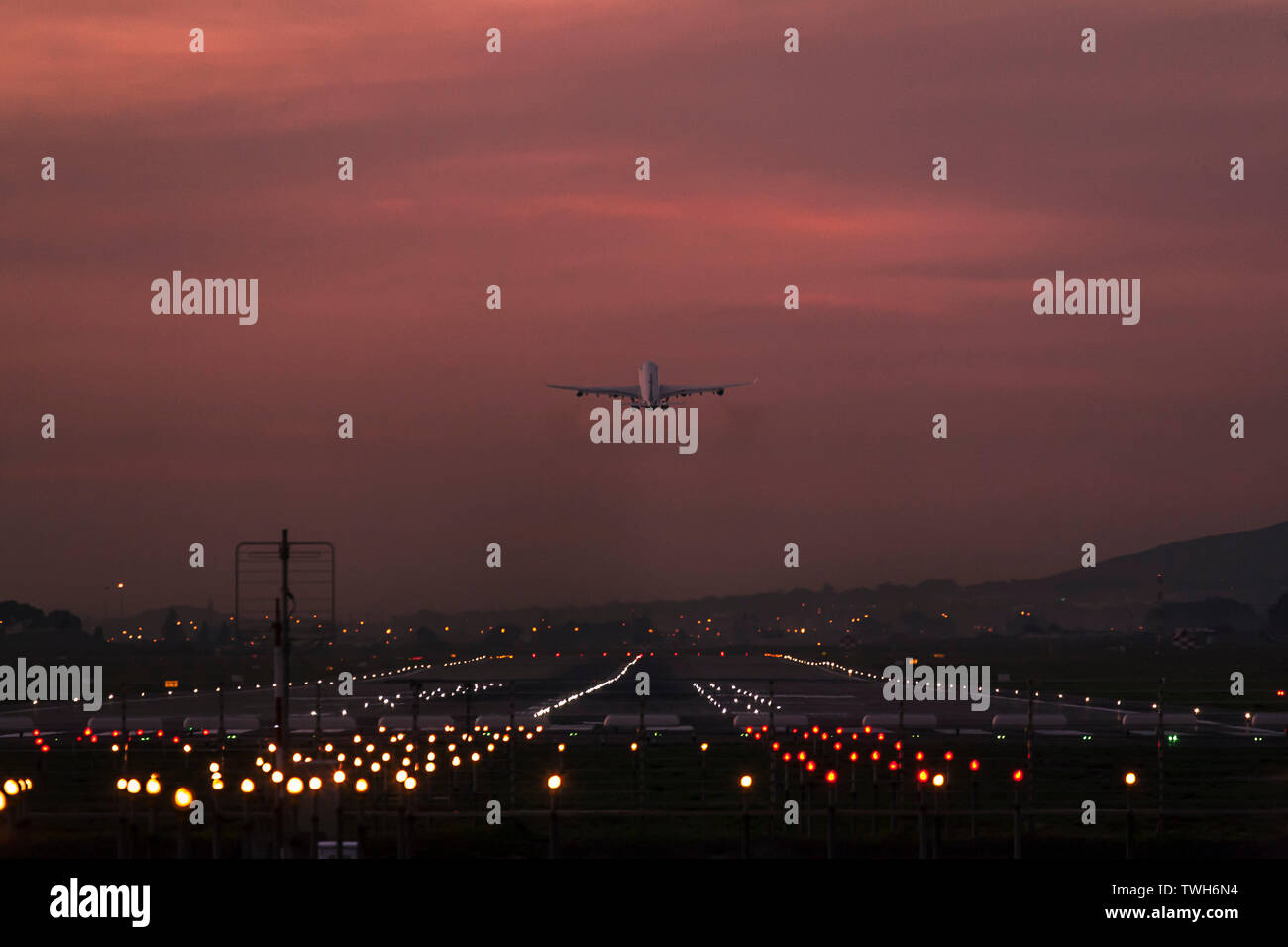 Los aviones de pasajeros partiendo desde el Aeropuerto Internacional de Ciudad del Cabo al anochecer con la pista de aterrizaje claramente iluminado. Foto de stock