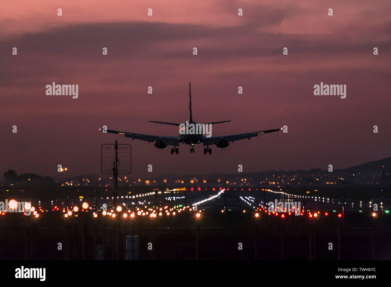 Los aviones de pasajeros de aterrizar en el Aeropuerto Internacional de Ciudad del Cabo al anochecer con la pista de aterrizaje claramente iluminado. Foto de stock