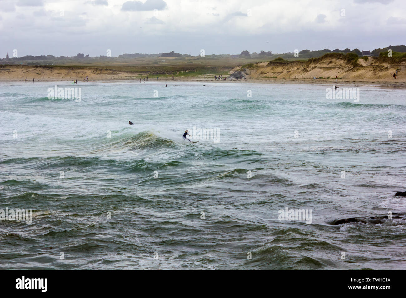 La costa bretona, con olas fuertes y un surfista cabalgando una ola Foto de stock
