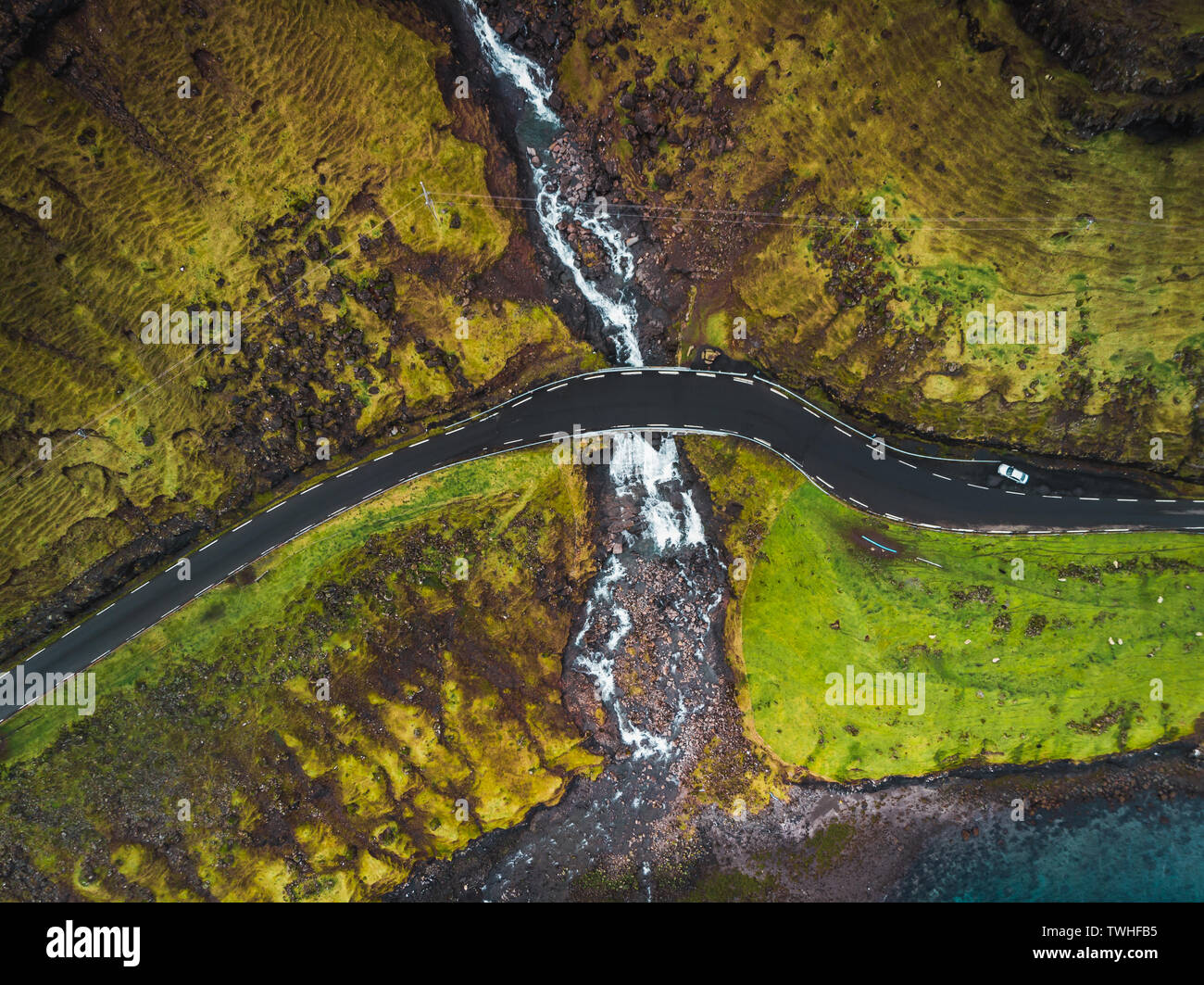 Imágenes aéreas de la Fosa de cascada desde arriba durante principios de la primavera con cumbres nevadas y verdes tonos (Islas Feroe, Dinamarca) Foto de stock