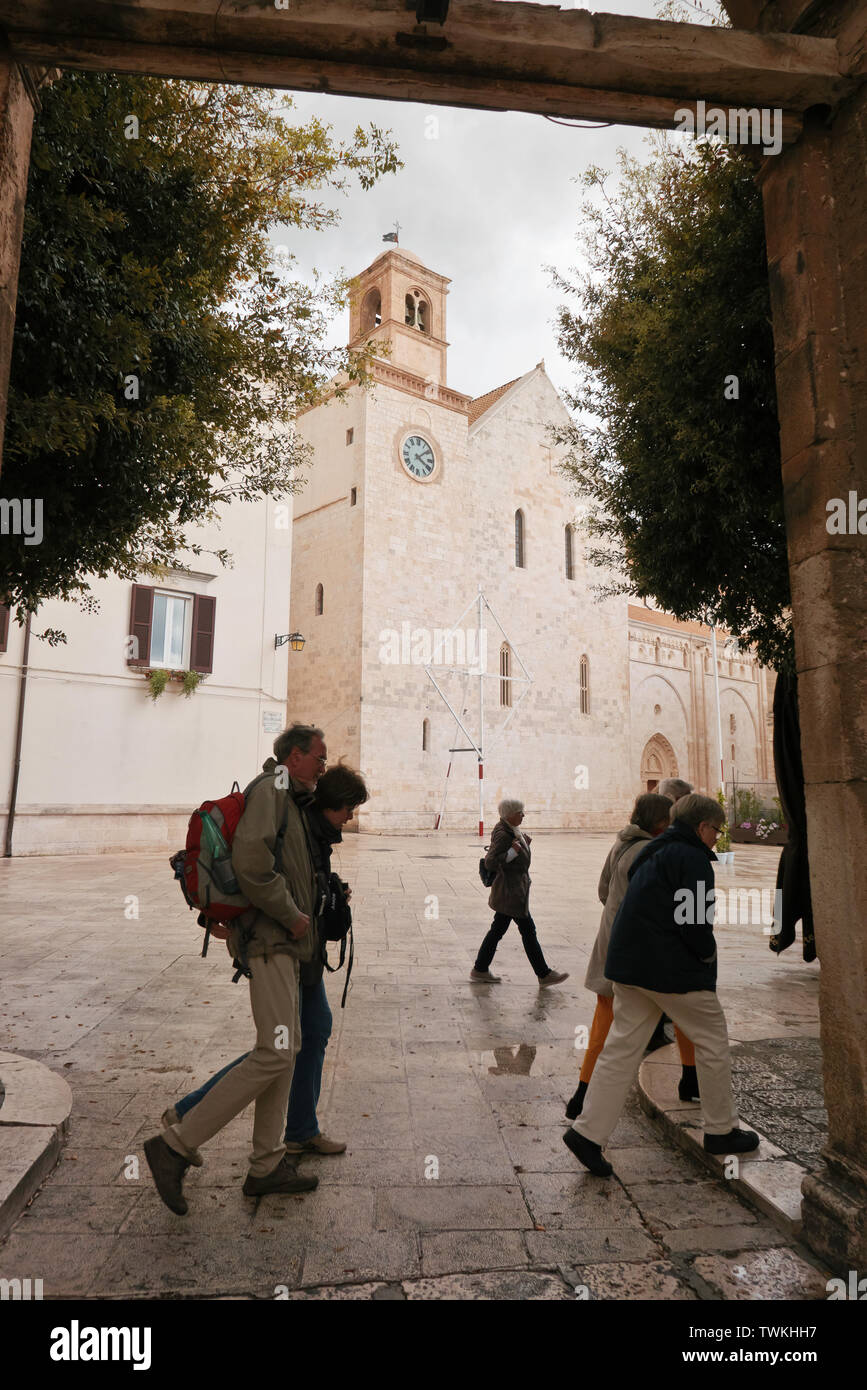 Conversano,Italia; grupo de turistas en el casco antiguo de Conversano una tarde nublada que caminar entre los edificios históricos . Foto de stock