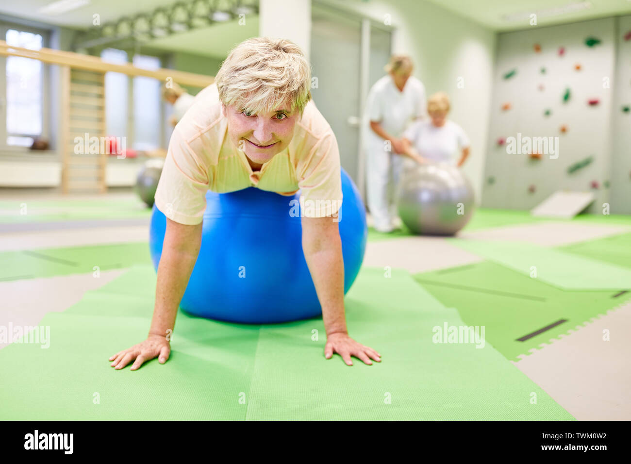 Mujer Senior está haciendo ejercicio en el ejercicio de pelota para volver formación en fisioterapia Foto de stock