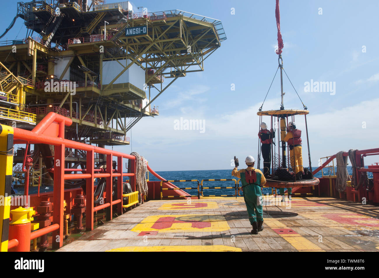La tripulación plataforma petrolera marina transferir personal alojamiento de barcazas a buques por grúa con cesta de personal de seguridad Foto de stock