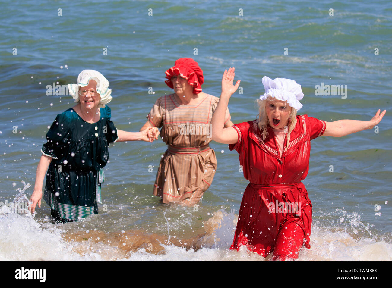 instante detective Oculto Broadstairs anual Festival Dickens. La playa Tea Party, tres mujeres mayores  remando en las olas en la orilla del mar en la época victoriana en trajes  de baño Fotografía de stock -