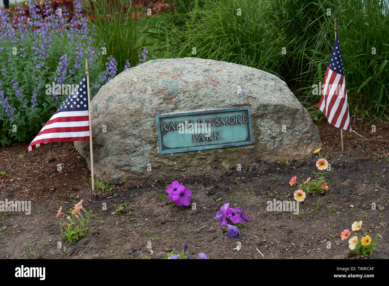 Jardín a Ralph P Bismore Parque con una piedra y placa y dos banderas  estadounidenses Fotografía de stock - Alamy