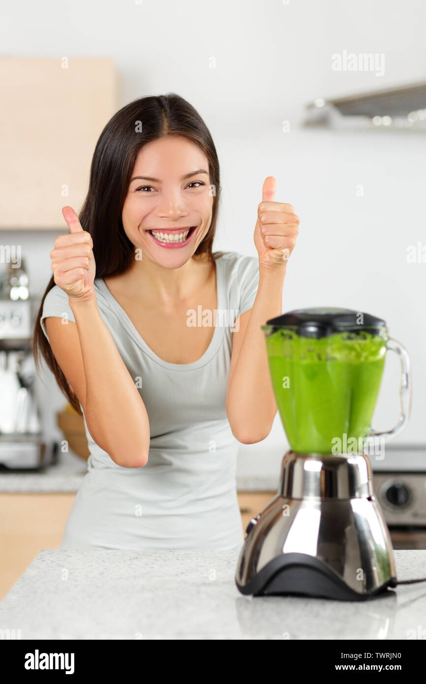 Batido vegetal mujer feliz Thumbs up mezcla batidos verdes Mujer haciendo batidos batido con la batidora. Comer sano