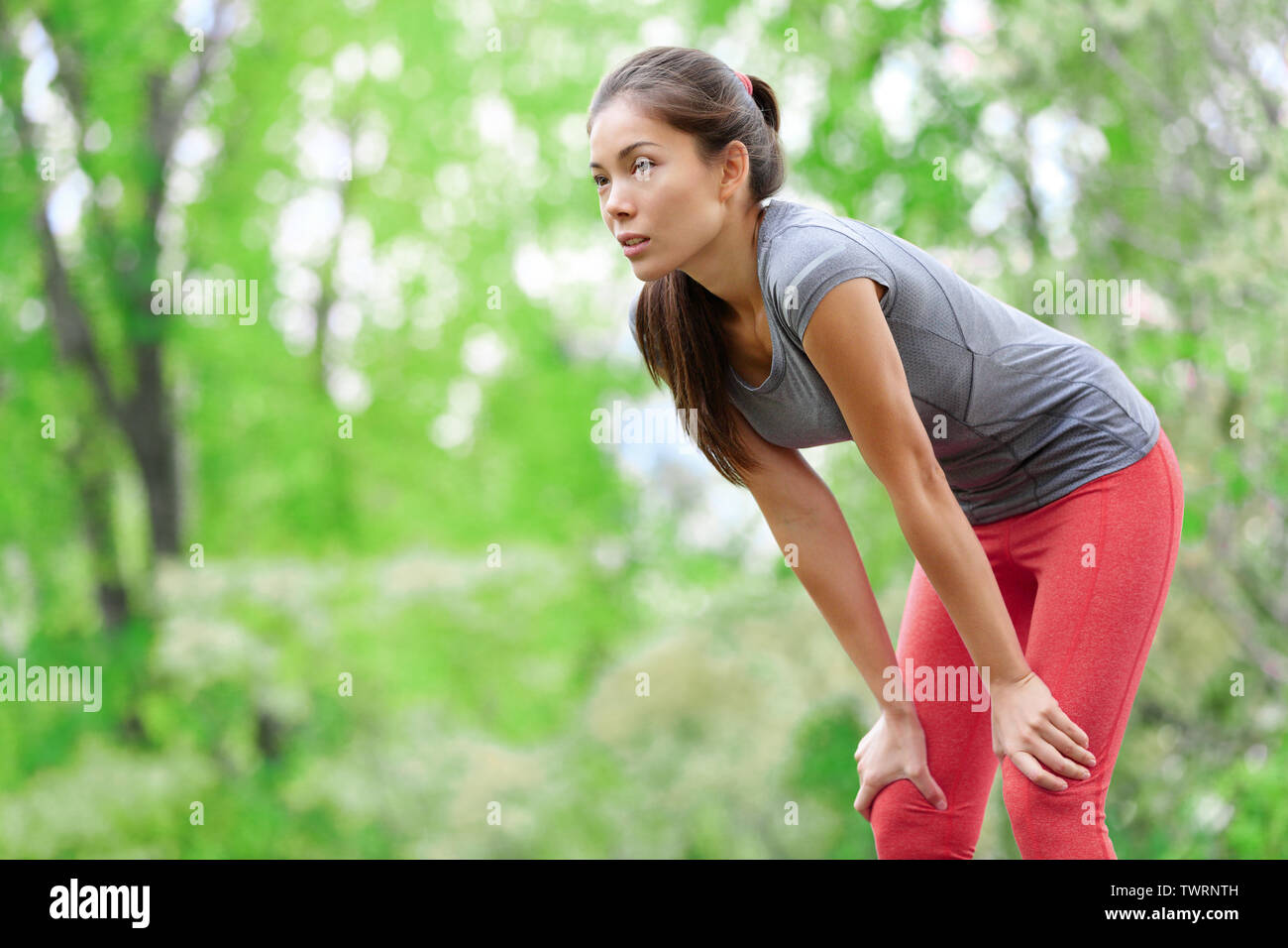 Mujer Asiática atleta runner descansando después de correr y entrenamiento de jogging al aire libre en el bosque. Cansado agotado hermoso gimnasio deportivo modelo de vivir el estilo de vida activo y saludable. Mestizos caucásicos de Asia. Foto de stock