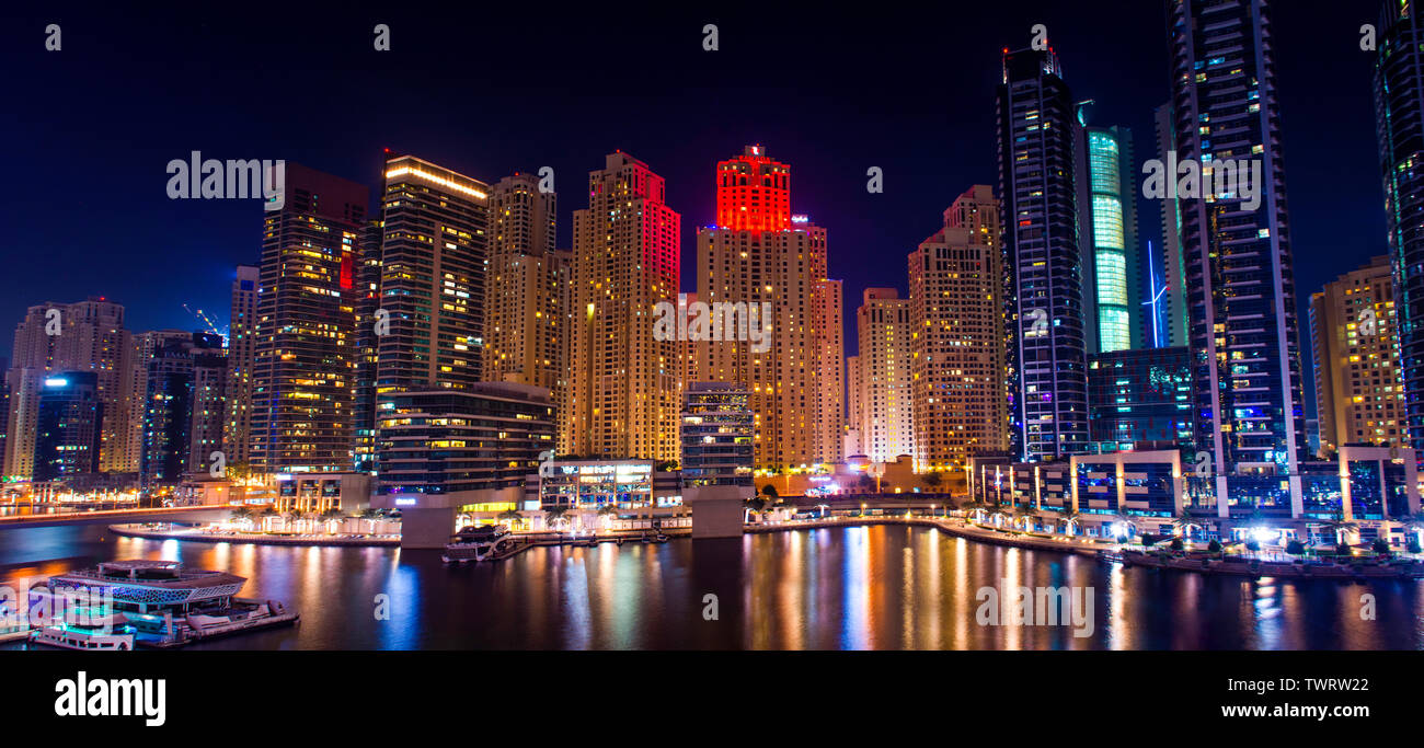 Vista nocturna de la ciudad de Dubai Marina edificios modernos y el lago en barco, yate de lujo de estilo de vida increíble arquitectura el mejor lugar para visitar Foto de stock