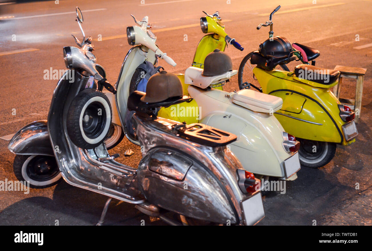 Classic Scooter en la noche por la carretera. Tres motos de época, negro, blanco y amarillo. La fotografía de la calle por la noche Foto de stock