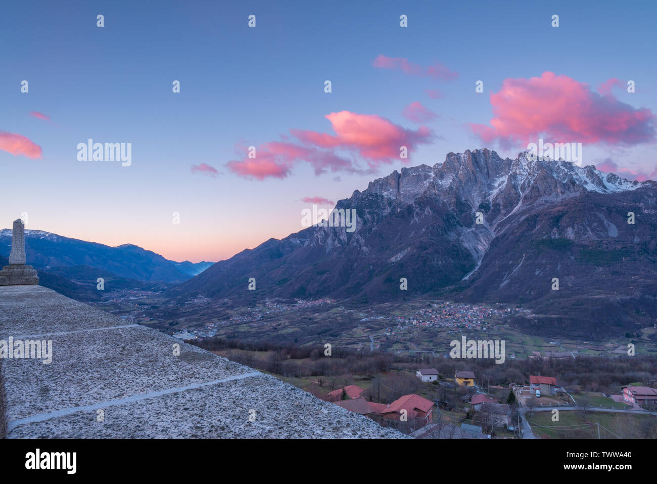 Amanecer sobre la ciudad de Cimbergo en Val Camonica, Italia. Nubes rosadas sobre las montañas, las nubes de colores al amanecer en el valle. Foto de stock