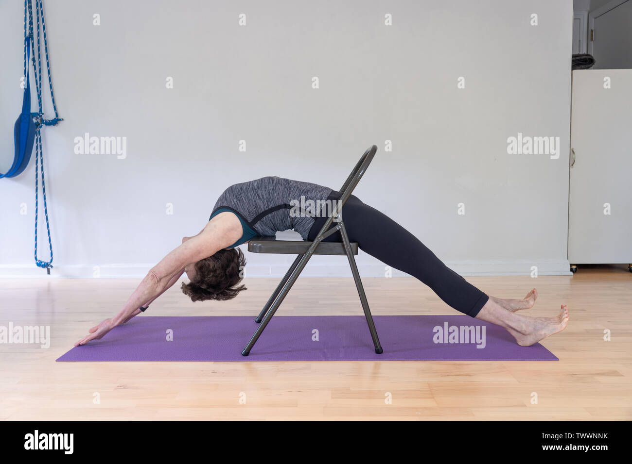 Una mujer de 70 años, instructor de yoga en su estudio muestra Iyengar Yoga  Silla Backbend Fotografía de stock - Alamy