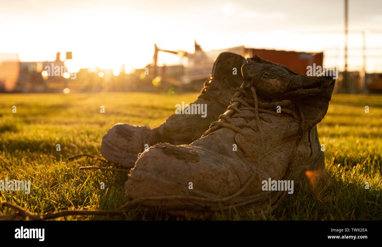 Botas de seguridad en un sitio de construcción cubierto de barro en frente  de una puesta de sol brillante Fotografía de stock - Alamy