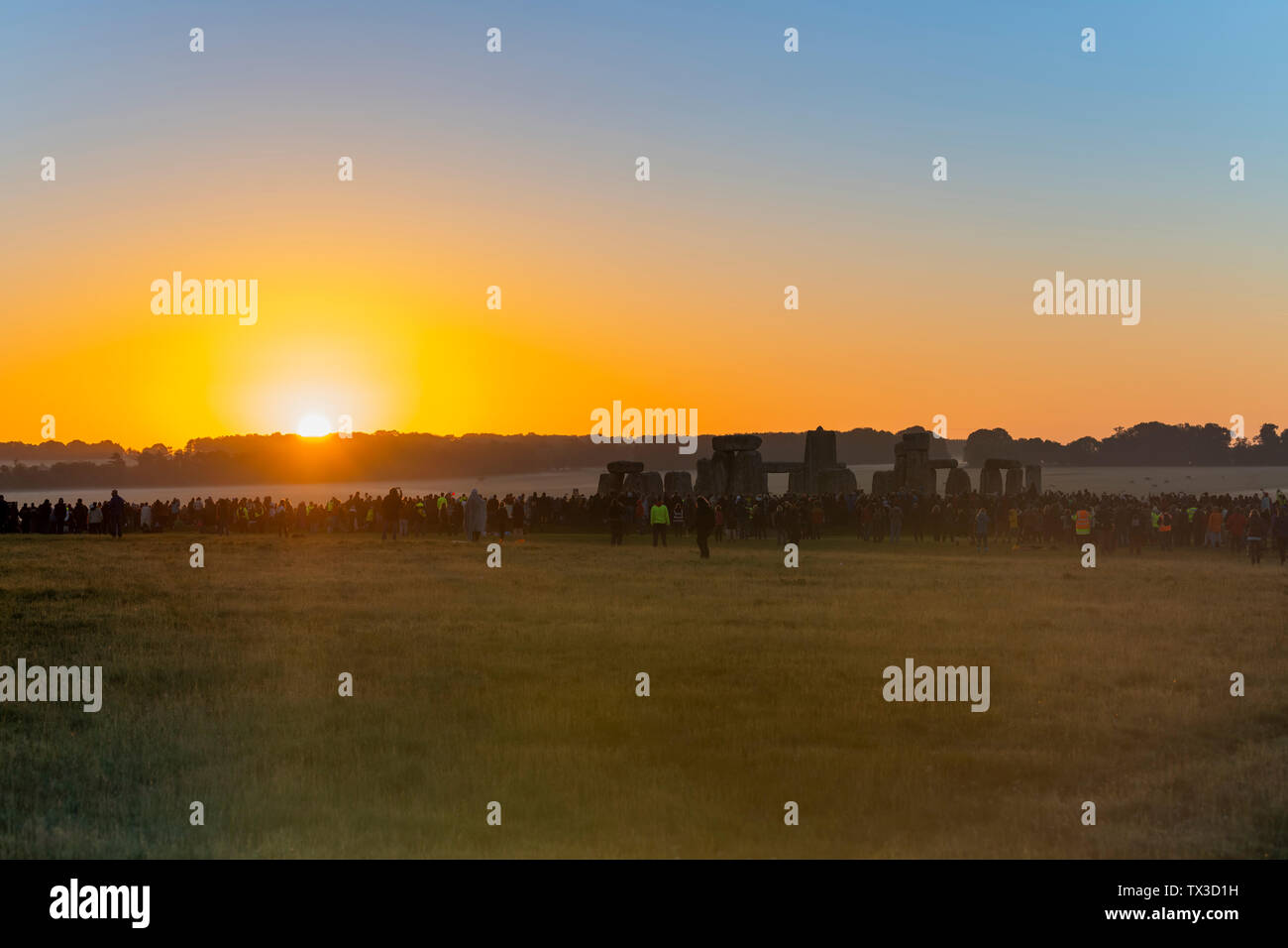 El 2019 el solsticio de verano en Stonehenge, Wiltshire, UK, ve una multitud en sus miles de esperar y ver salir el sol en el día más largo. Foto de stock