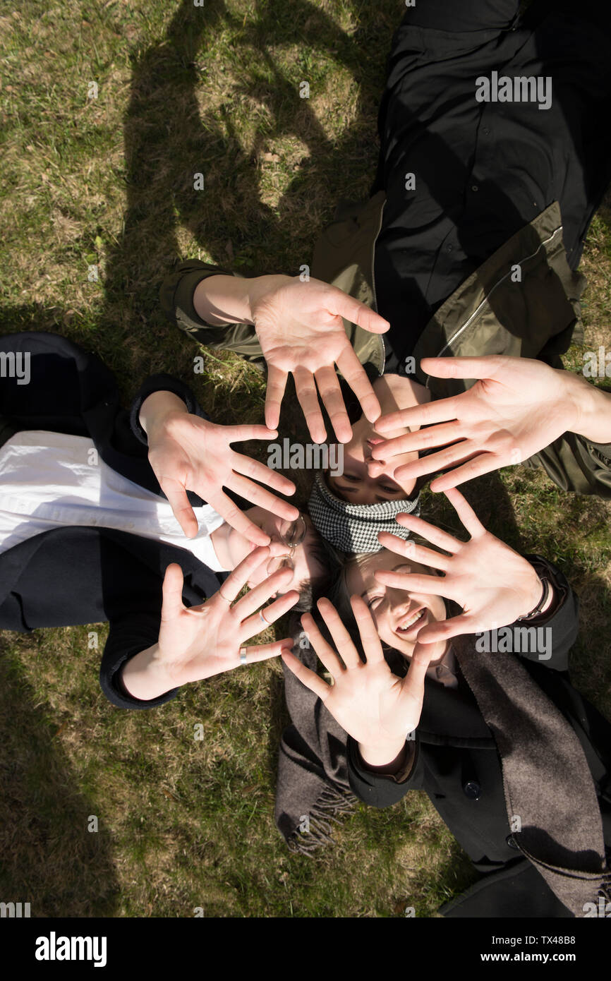 Grupo de mujeres jóvenes tumbados en la hierba formando una estrella con sus manos Foto de stock