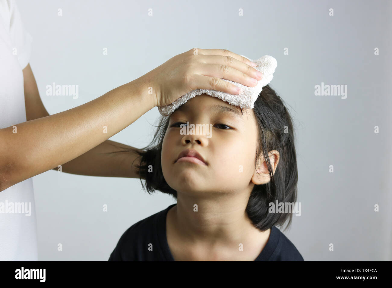 La madre se frota el cuerpo con un paño húmedo para kid para reducir la