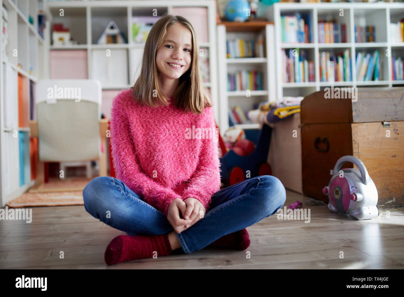Seguro chica sentada con las piernas cruzadas en el piso de su habitación Foto de stock