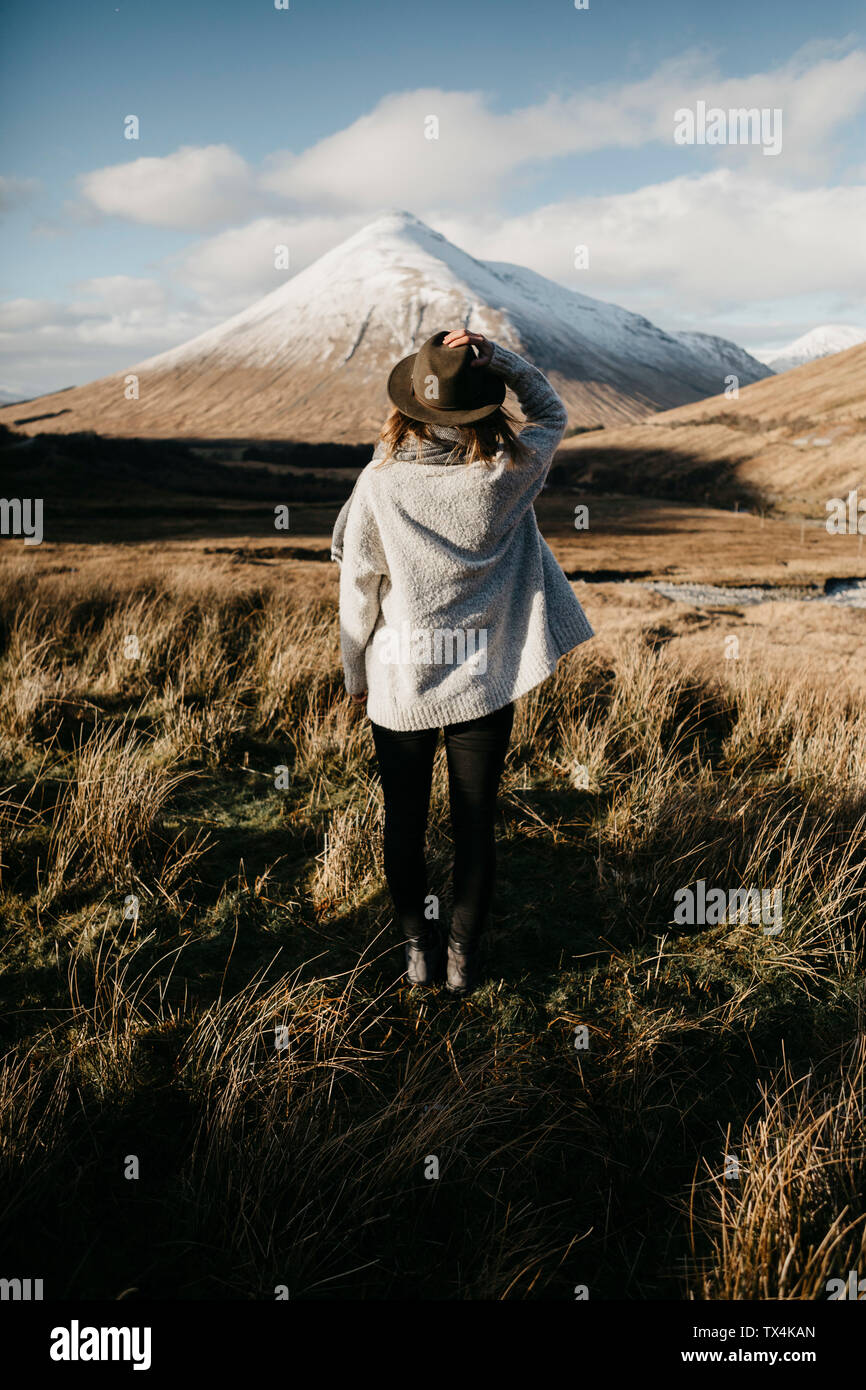 Reino Unido, Escocia, Loch Lomond y los Trossachs National Park, vista trasera de la mujer joven de pie en el paisaje rural de montaña mirando Foto de stock