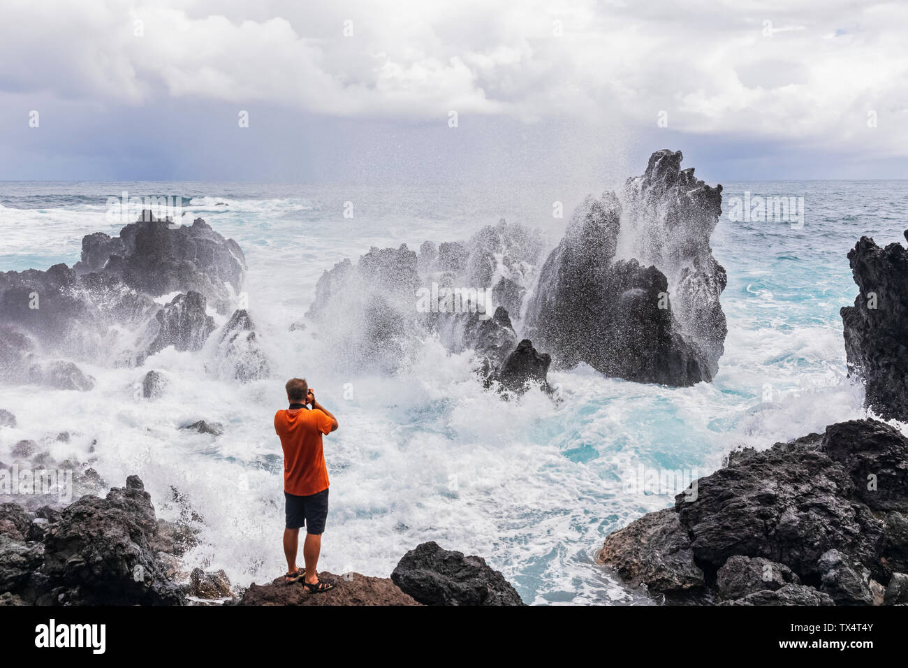 Ee.Uu., Hawai, Isla Grande, Laupahoehoe Beach Park,hombre tomando fotos de Rompiendo olas en la costa rocosa Foto de stock