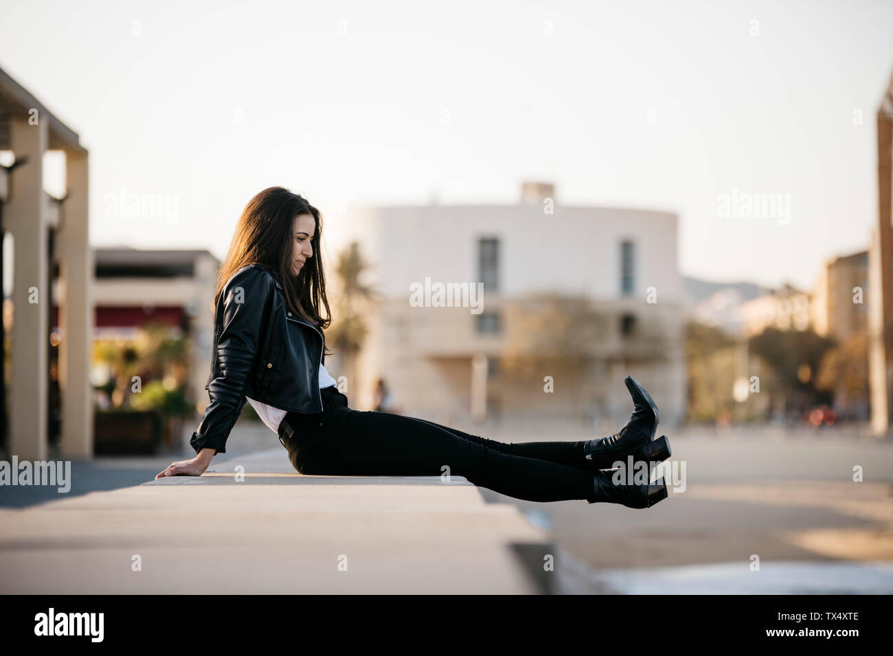Mujer joven sentada en una pared. Foto de stock