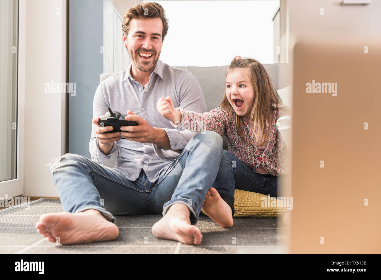 Joven y pequeña niña jugando juego de ordenador con consola de videojuegos Foto de stock