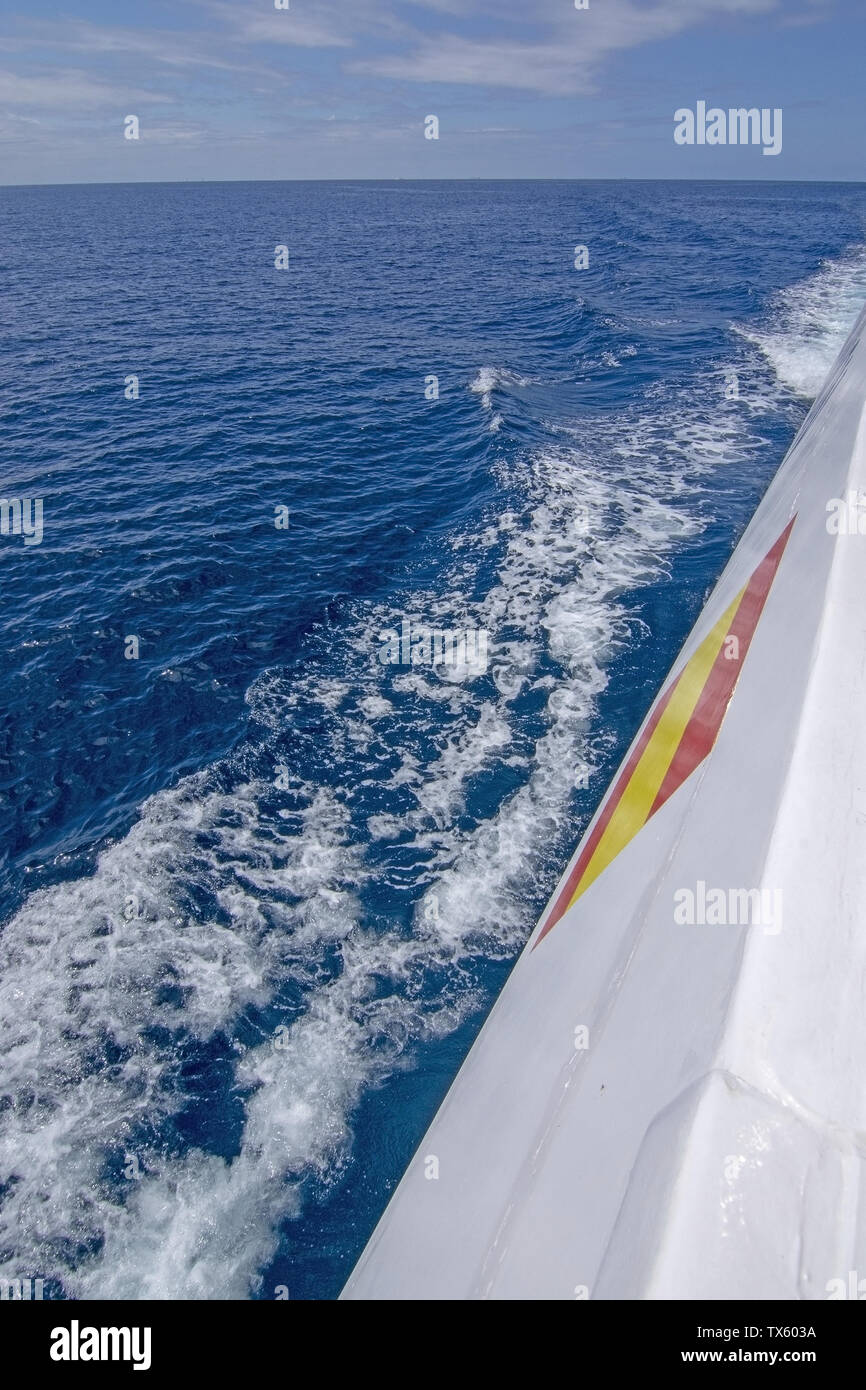 Blanco lado barco con bandera española espumosa y azul mar Mediterráneo con sky en Mallorca, España imágenes verticales. Foto de stock