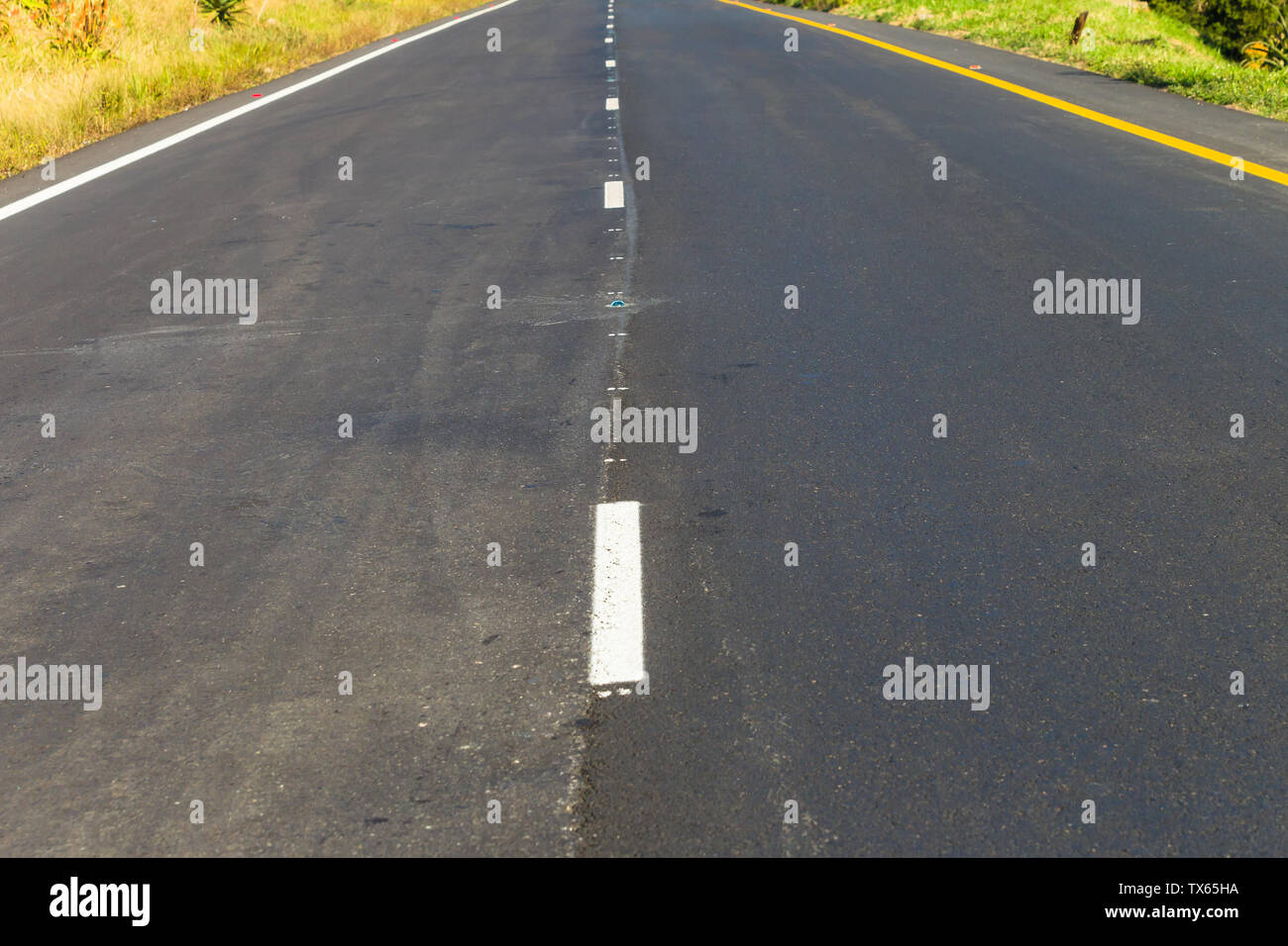 Autopista carretera de dos carriles nuevo asfalto y líneas pintadas recto sin vehículos disminuyendo la perspectiva. Foto de stock