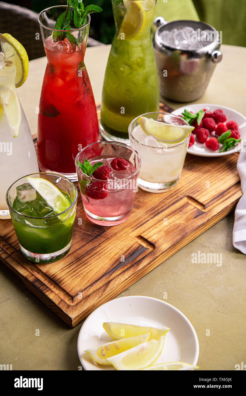 Los refrescos de verano, un conjunto de las limonadas. Las limonadas en jarras sobre la mesa, los ingredientes que los componen están dispuestas alrededor. Foto de stock