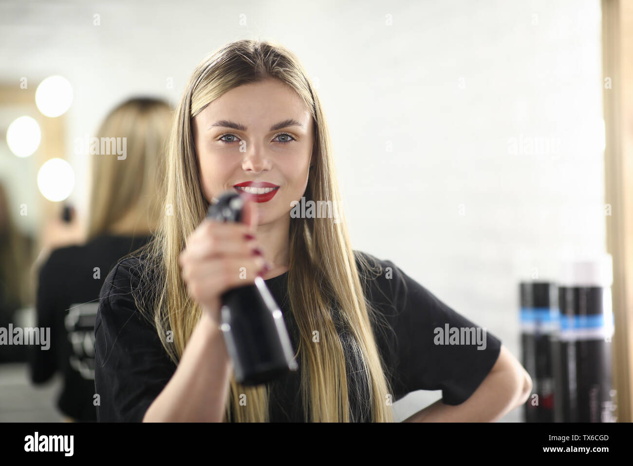 Chica Peluquería sosteniendo la botella pulverizador de agua. Mujer  estilista con spray en un salón de belleza. Esteticista con labios rojos y  el pelo largo. Belleza ingenio femenino Fotografía de stock 